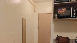 Uma cozinha compacta com micro-ondas, uma geladeira pequena e uma mesa posta para refeições.