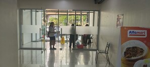 A hallway with a glass door leading to an outdoor area, a wet floor sign, and a food hall sign. - Beautiful Tower with AC in Peaceful Cubao City Neighborhood (Quezon City)