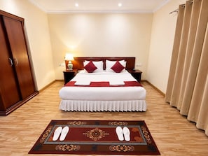 A hotel room with a bed, nightstands, a wardrobe, and a carpet. - The Orchid Hotel (Phuentosholing)