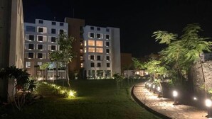 A nighttime view of a hotel with illuminated windows and a well-lit garden area. - Vinti Resort, Ambaji (Danta)