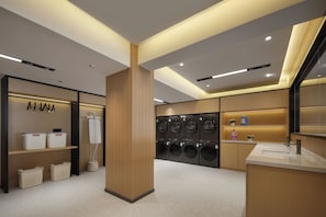 Un moderno cuarto de lavandería con varias lavadoras, una zona de secado y estantes ordenados con cestas de ropa.