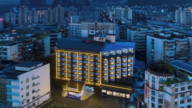 A hotel with multiple floors, a central courtyard, and a view of surrounding buildings and mountains.