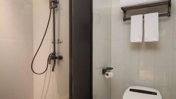 A modern bathroom with a glass-enclosed shower, a toilet, and a towel rack.