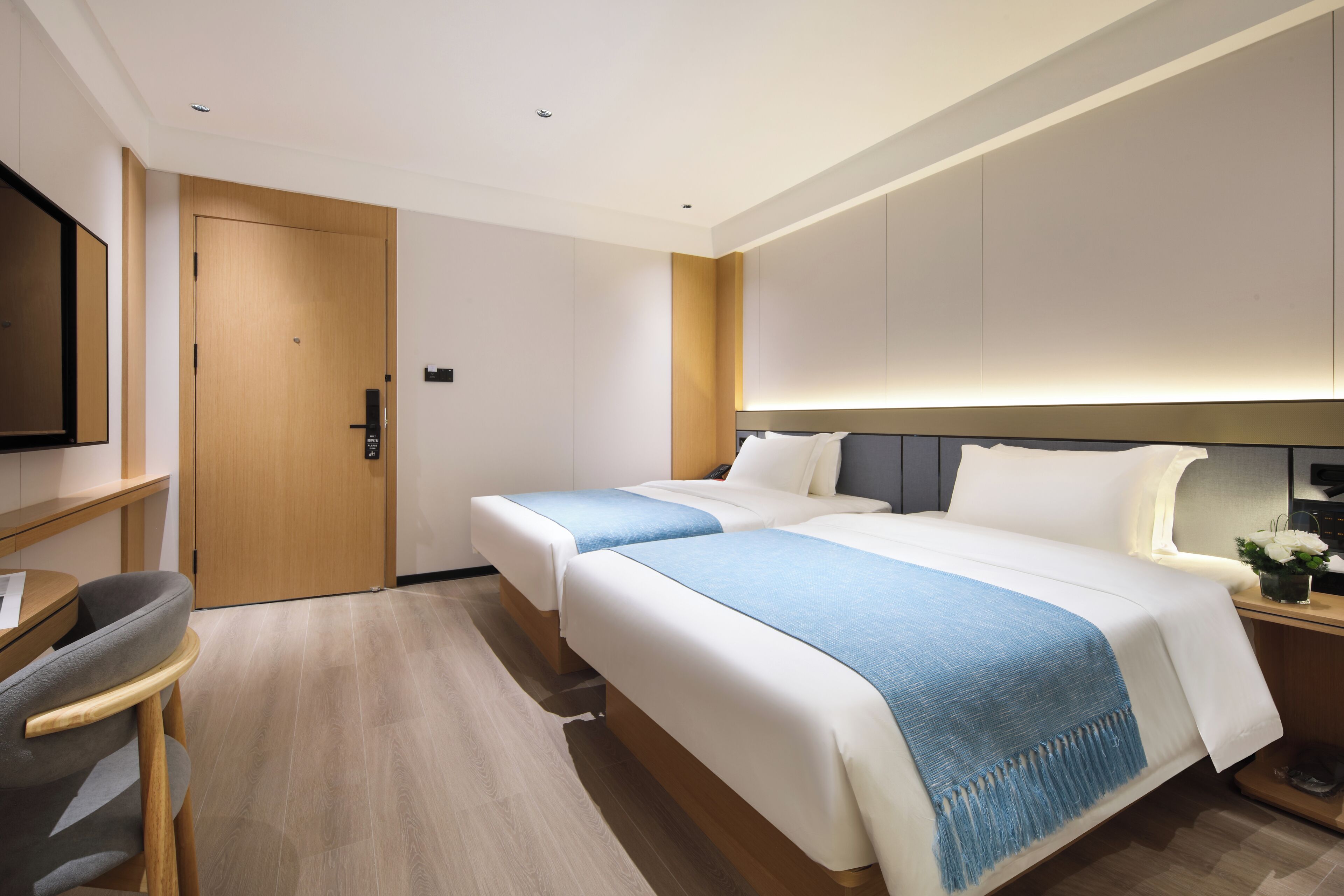 Quarto de hotel com duas camas, uma mesa e uma televisão.