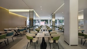 A spacious indoor dining area with multiple tables and chairs, large windows, and a modern interior design.