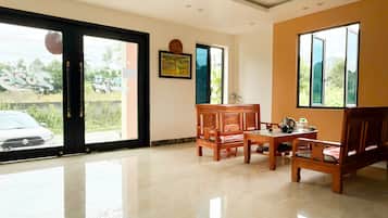 A room with a large sliding glass door, a ceiling fan, a framed picture on the wall, and a wooden table with chairs.