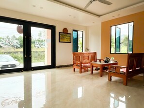 A room with a large sliding glass door, a ceiling fan, a framed picture on the wall, and a wooden table with chairs.
