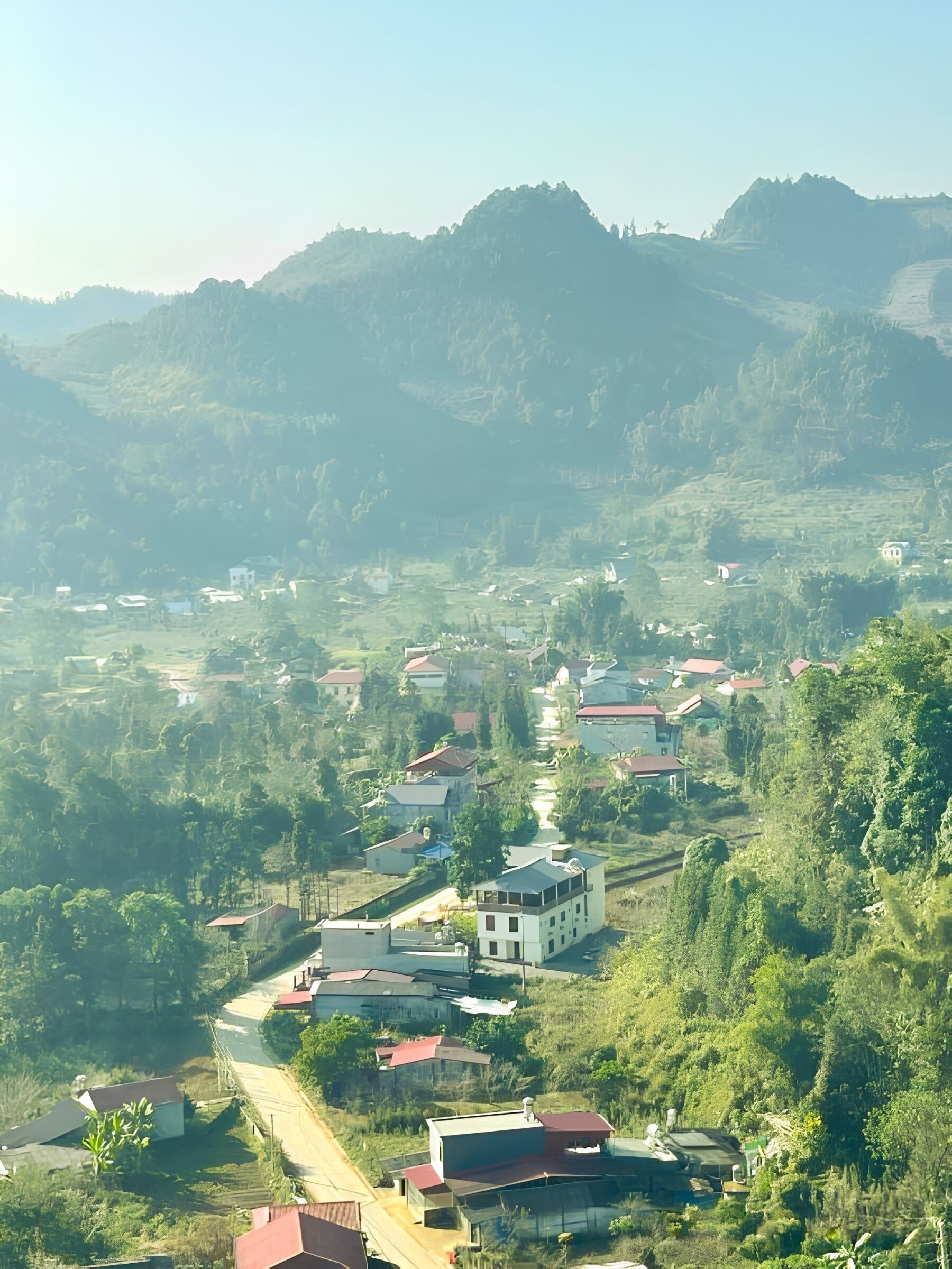 A rural village with houses and terraced fields, surrounded by hills.
