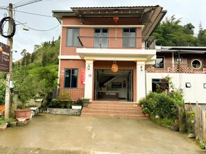 A two-story building with a balcony and a staircase leading to the entrance.