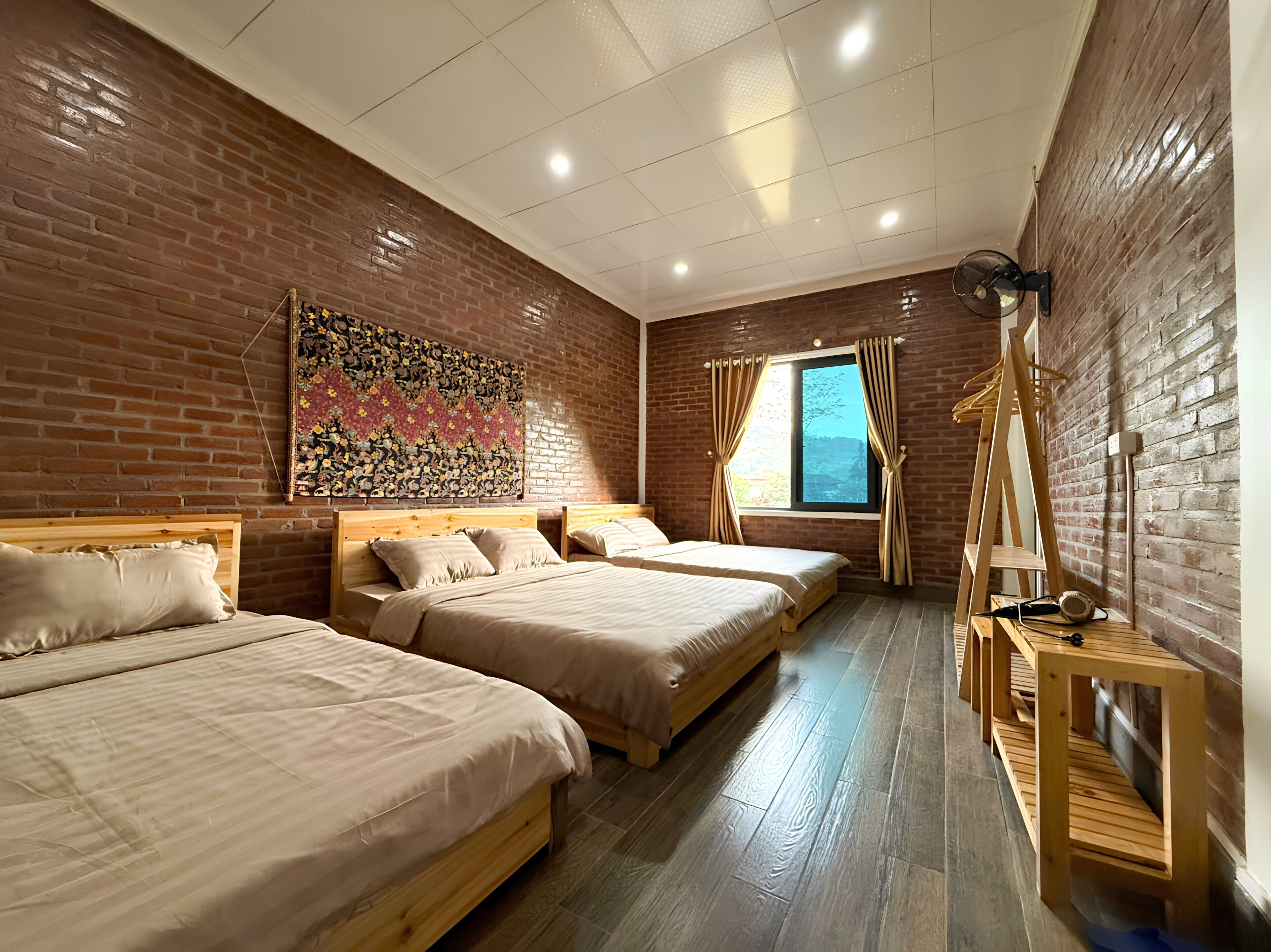 A room with two wooden beds, a brick wall, a window with curtains, and a wooden ladder.