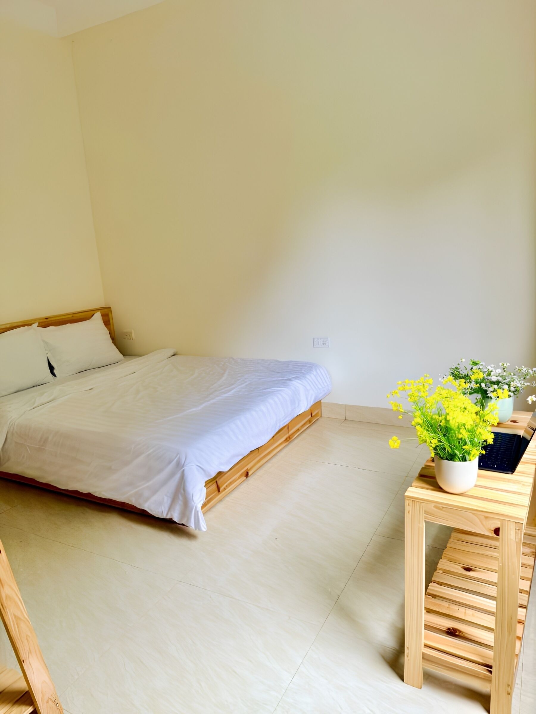 Ein Schlafzimmer mit einem Bett, einem Nachttisch aus Holz und einer Zimmerpflanze.