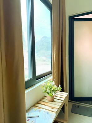 A window with curtains, a potted plant, and a desk with a calculator and papers.