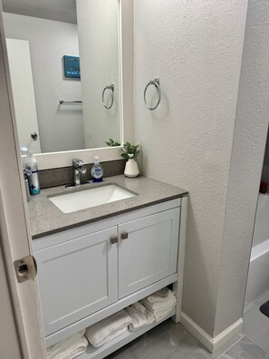 A bathroom with a white sink, a mirror, a towel rack, and a small potted plant. - Beaver Lake Waterfront Retreat (Rogers)