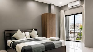 A modern bedroom with a large bed, a wardrobe, and a balcony with a view. - The One Rooms (Tambon Rawai)