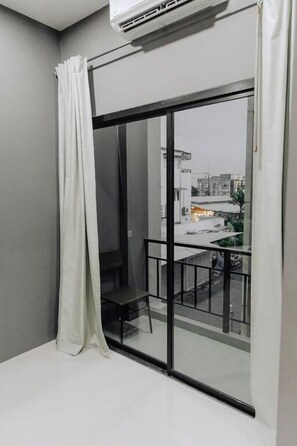 A room with a sliding glass door leading to a balcony with a metal railing. - The One Rooms (Tambon Rawai)