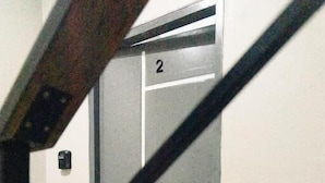 A stairwell with a metal elevator door marked with the number 2. - The One Rooms (Tambon Rawai)