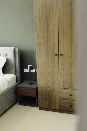 A bedroom with a bed, a nightstand, and a wooden wardrobe. - The One Rooms (Tambon Rawai)