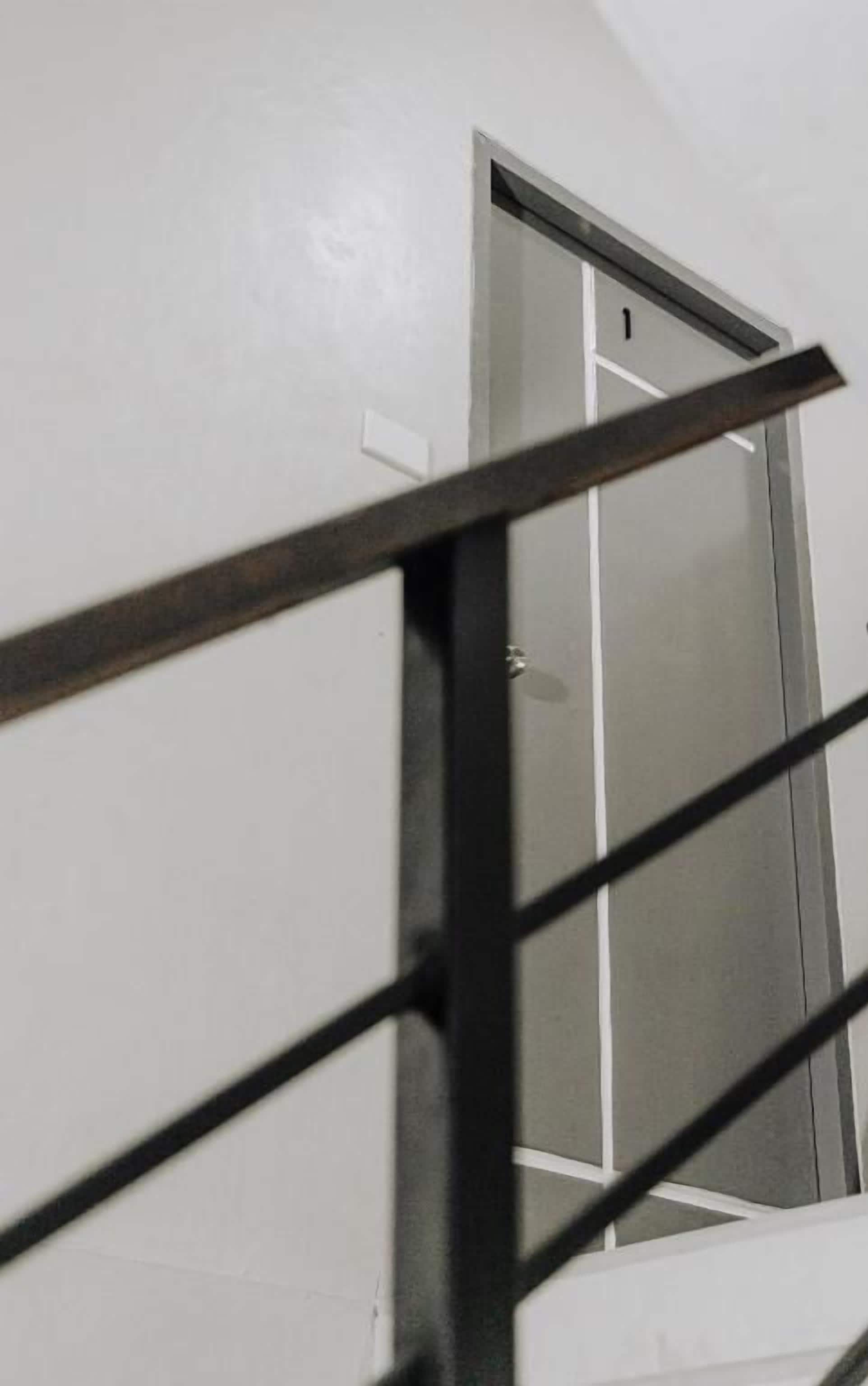 Escada com corrimão de metal que leva a uma porta com o número 1.