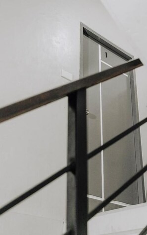 Escada com corrimão de metal que leva a uma porta com o número 1.