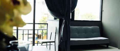 A room with a sofa, a table with glasses, and a window with curtains.