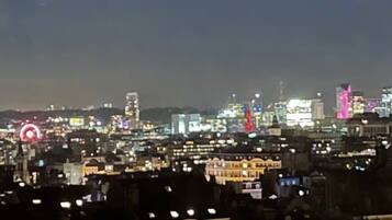 Une vue nocturne d’une ville, avec des bâtiments illuminés et une imposante structure en forme de dôme.