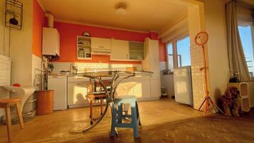 A kitchen with a glass table, white cabinets, and a blue stool.