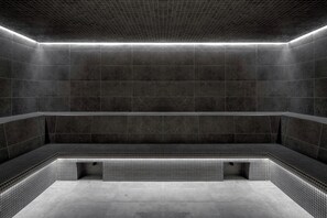 A modern, dimly lit indoor swimming pool with dark tiled walls and a bench along the edge. - Marina Bay Riviera Hotel, Curio Collection by Hilton (Villeneuve-Loubet)