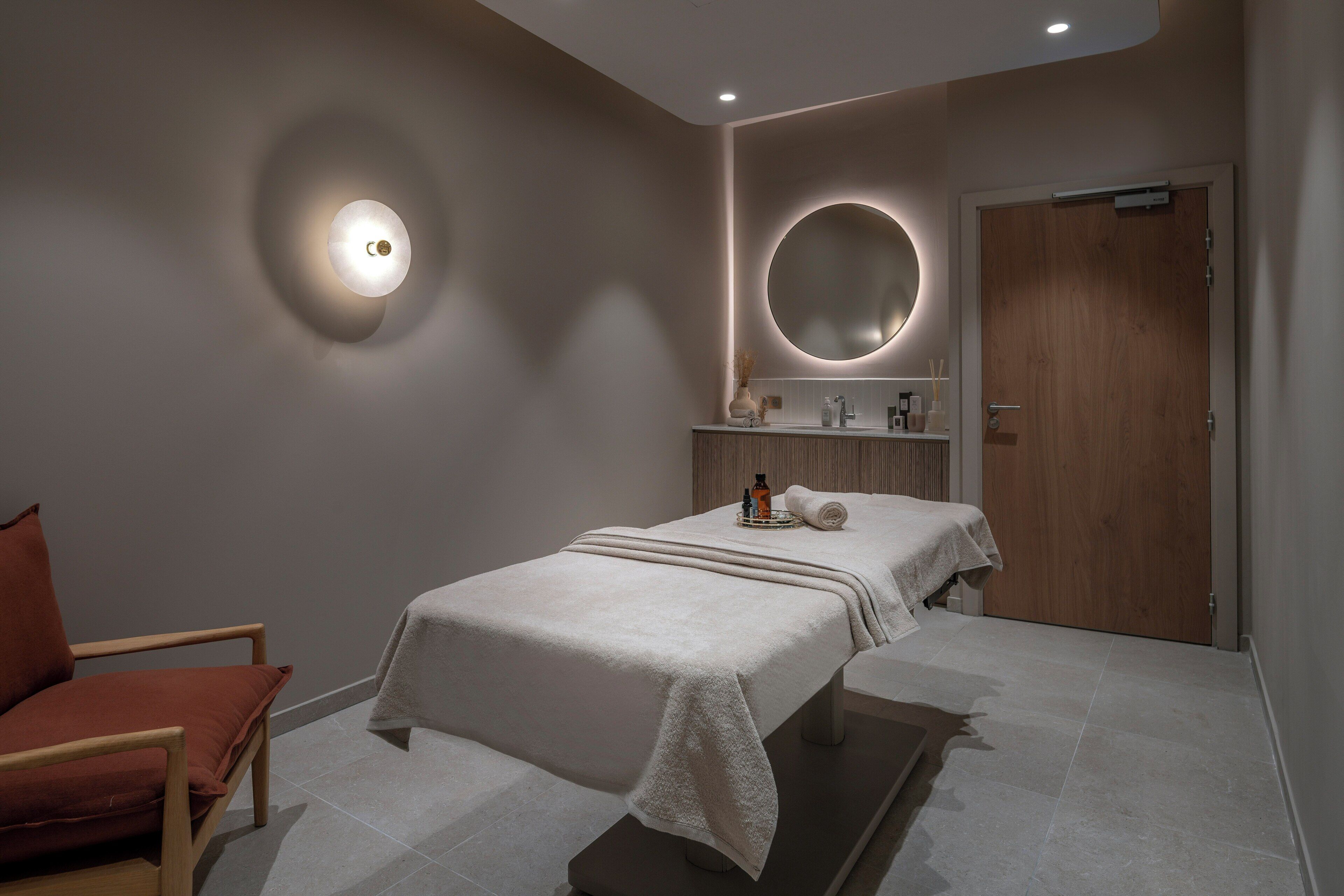 Un dormitorio moderno con una cama, una silla, un espejo y una puerta.