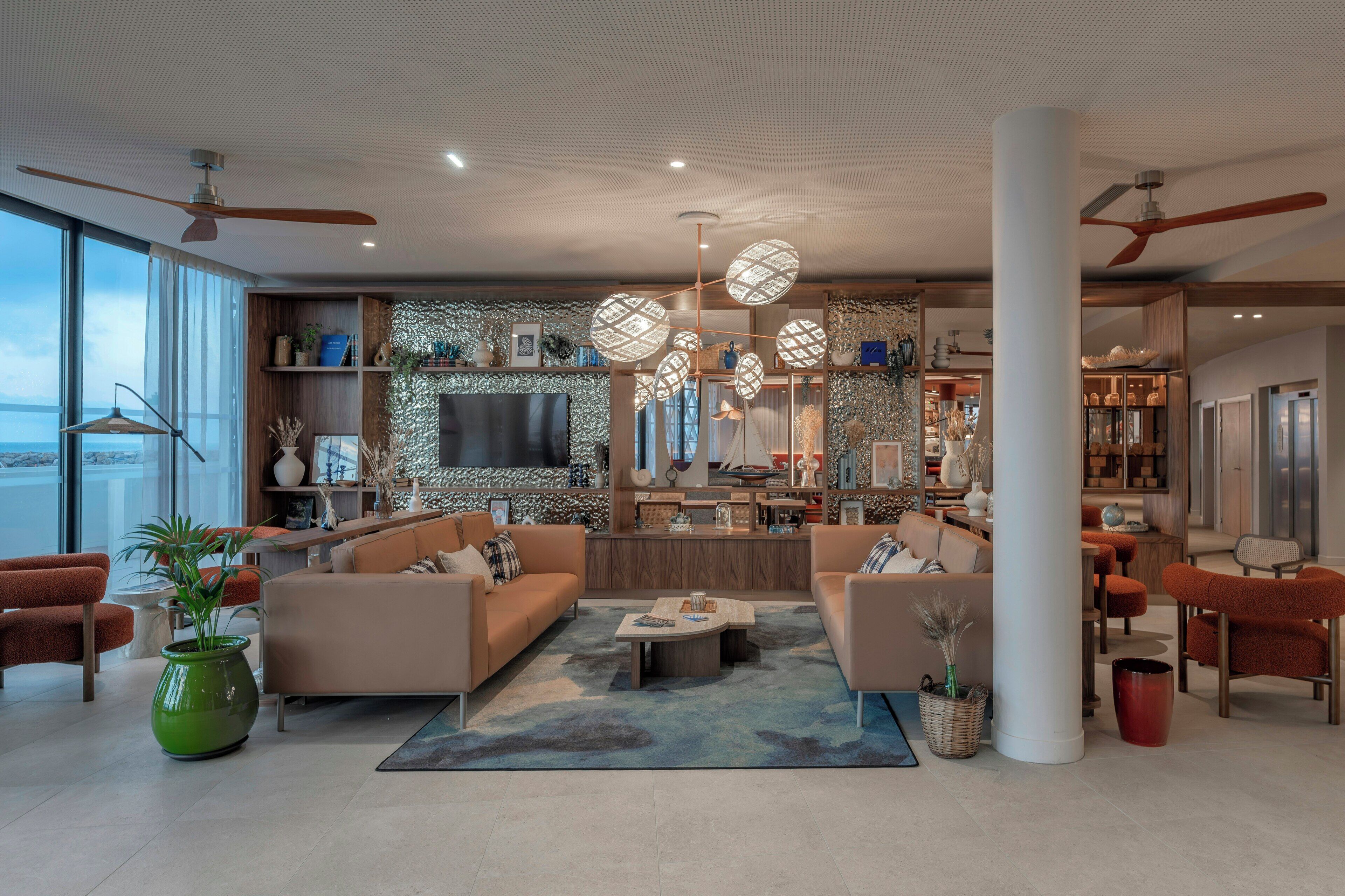 A spacious living area with a large flat-screen TV, comfortable seating, and a view of the sea.