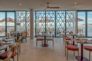 Uma ampla sala de jantar com grandes janelas que oferecem vista para a praia.