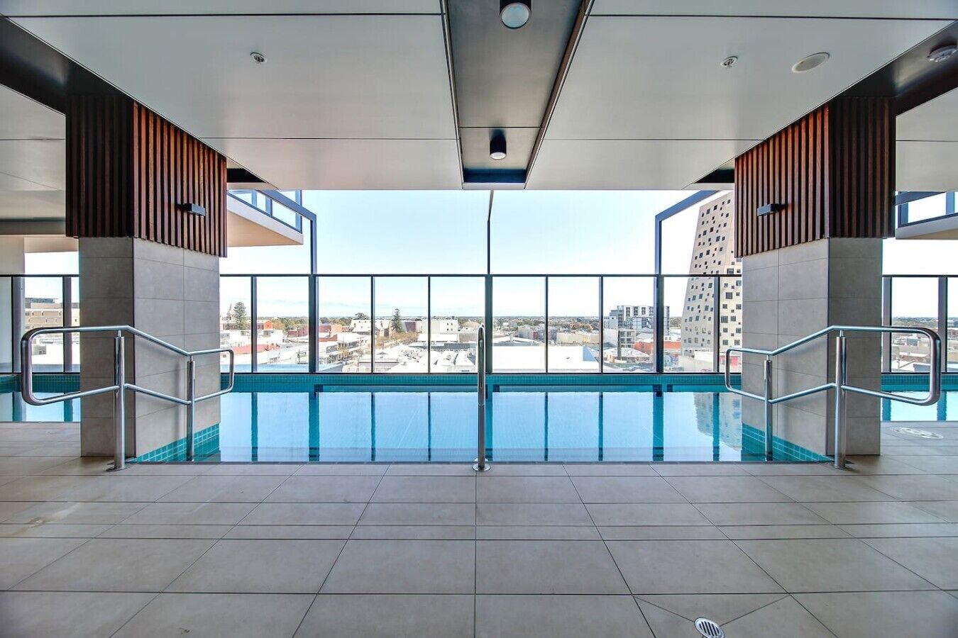 A modern indoor swimming pool with a view of the cityscape.
