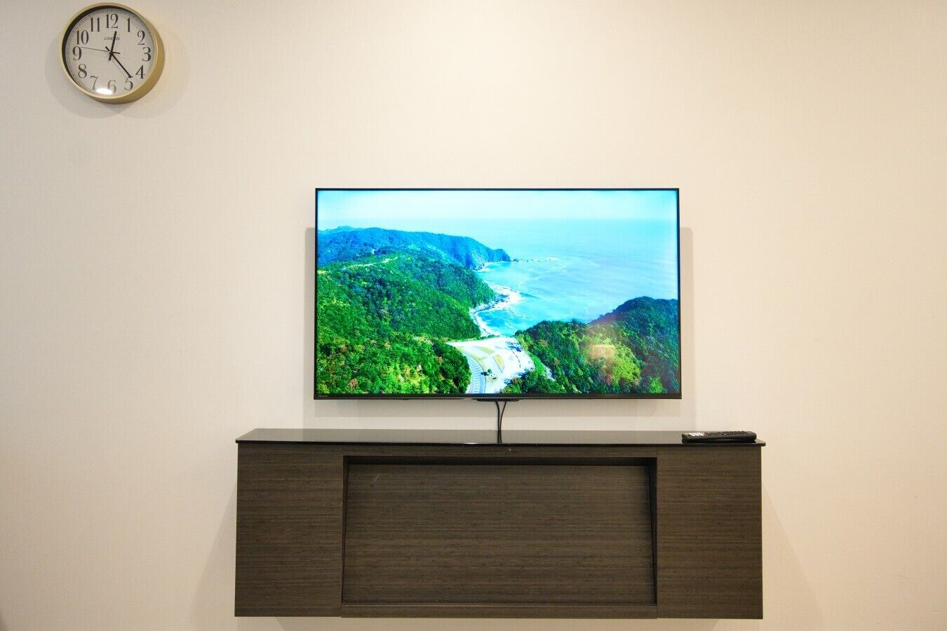 Ein Flachbildfernseher ist an einer Wand über einem dunklen Holzschrank angebracht.
