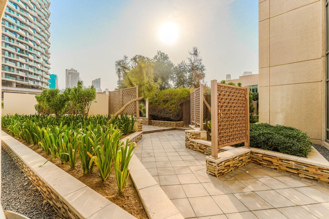 A landscaped outdoor area with a pathway, wooden fences, and various plants.