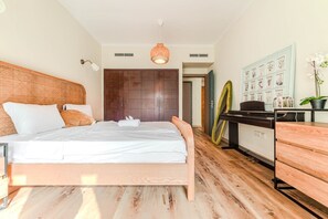 Ein Schlafzimmer mit einem Bett, einem Schreibtisch, einem Stuhl, einem Kleiderschrank und einer Wand mit gerahmten Bildern.