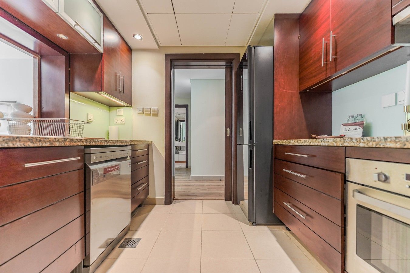 A modern kitchen with wooden cabinets, stainless steel appliances, and a tiled floor.