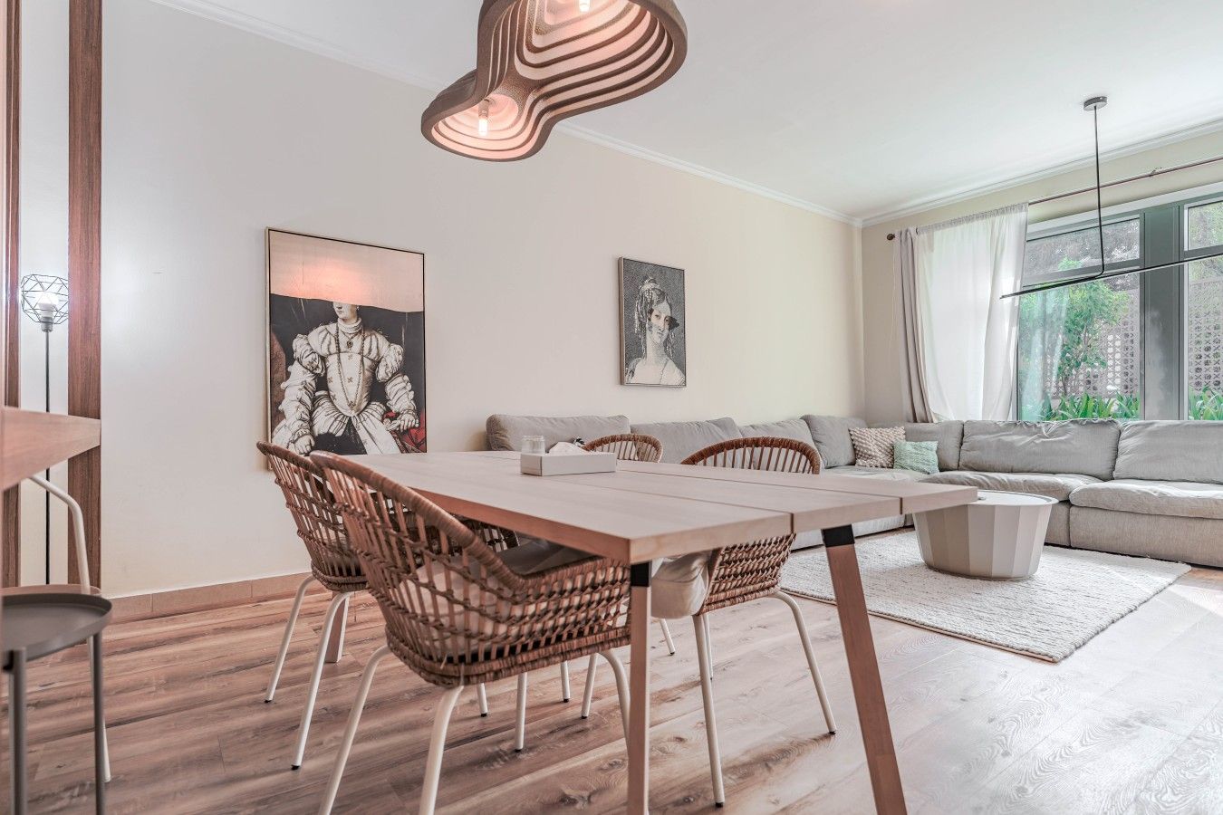 Een moderne woonkamer met een eetgedeelte, met een zithoek, een eettafel met stoelen en kunstwerken aan de muren.