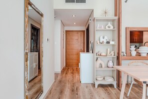 A hallway with a wooden door, a white refrigerator, and a dining area with a table and chairs. - HAVN - Spacious One Bedroom in Downtown Dubai (Dubai)