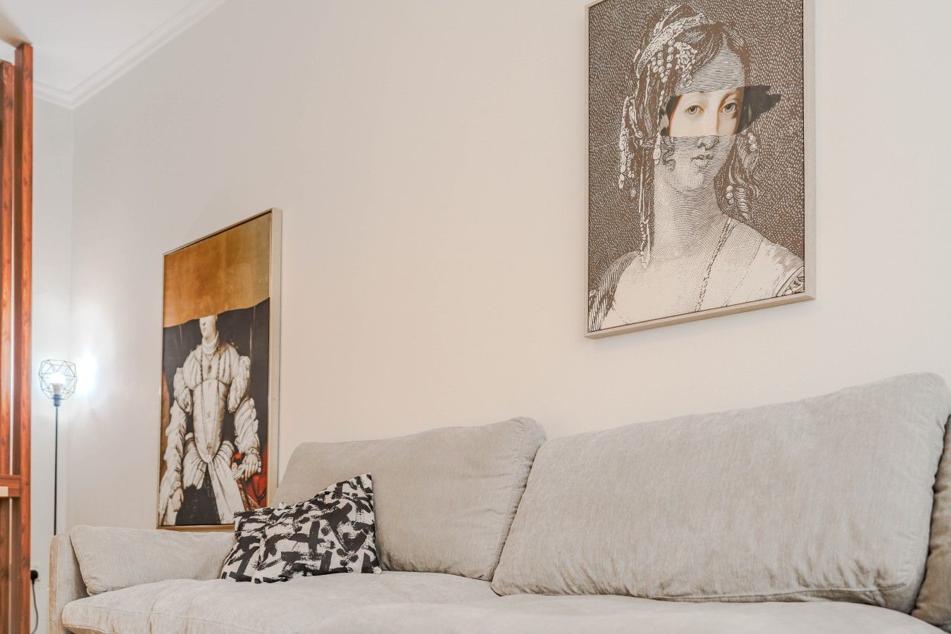 Un salon avec un canapé, un coussin à motifs et deux œuvres d’art accrochées au mur.