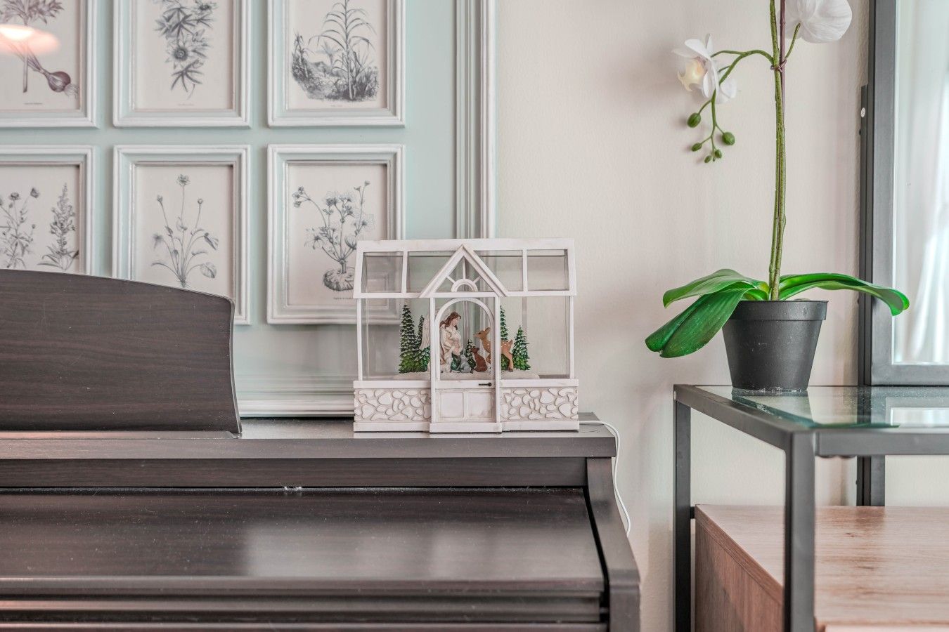 Un piano sur lequel sont posés un modèle de maison décoratif et une plante en pot, le tout sur une table.