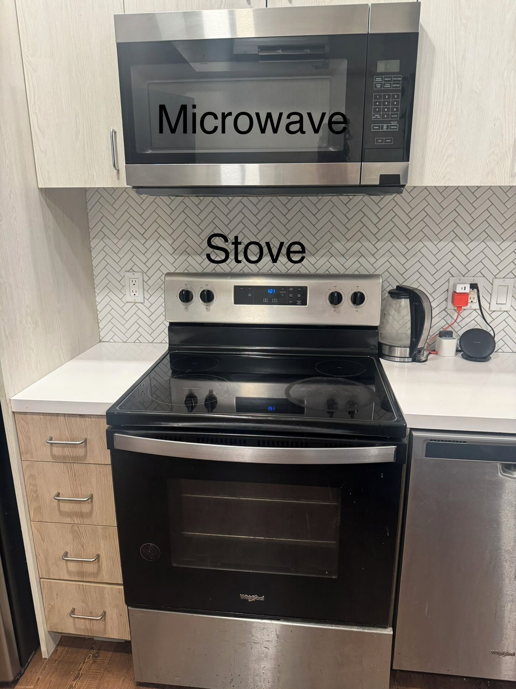 Une cuisine avec un four à micro-ondes placé au-dessus de la cuisinière, un lave-vaisselle sur la droite et un pare-feu en motif chevrons.