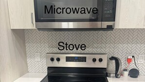 Una cocina con microondas sobre la estufa, lavavajillas a la derecha y salpicadero con motivo de espiga.