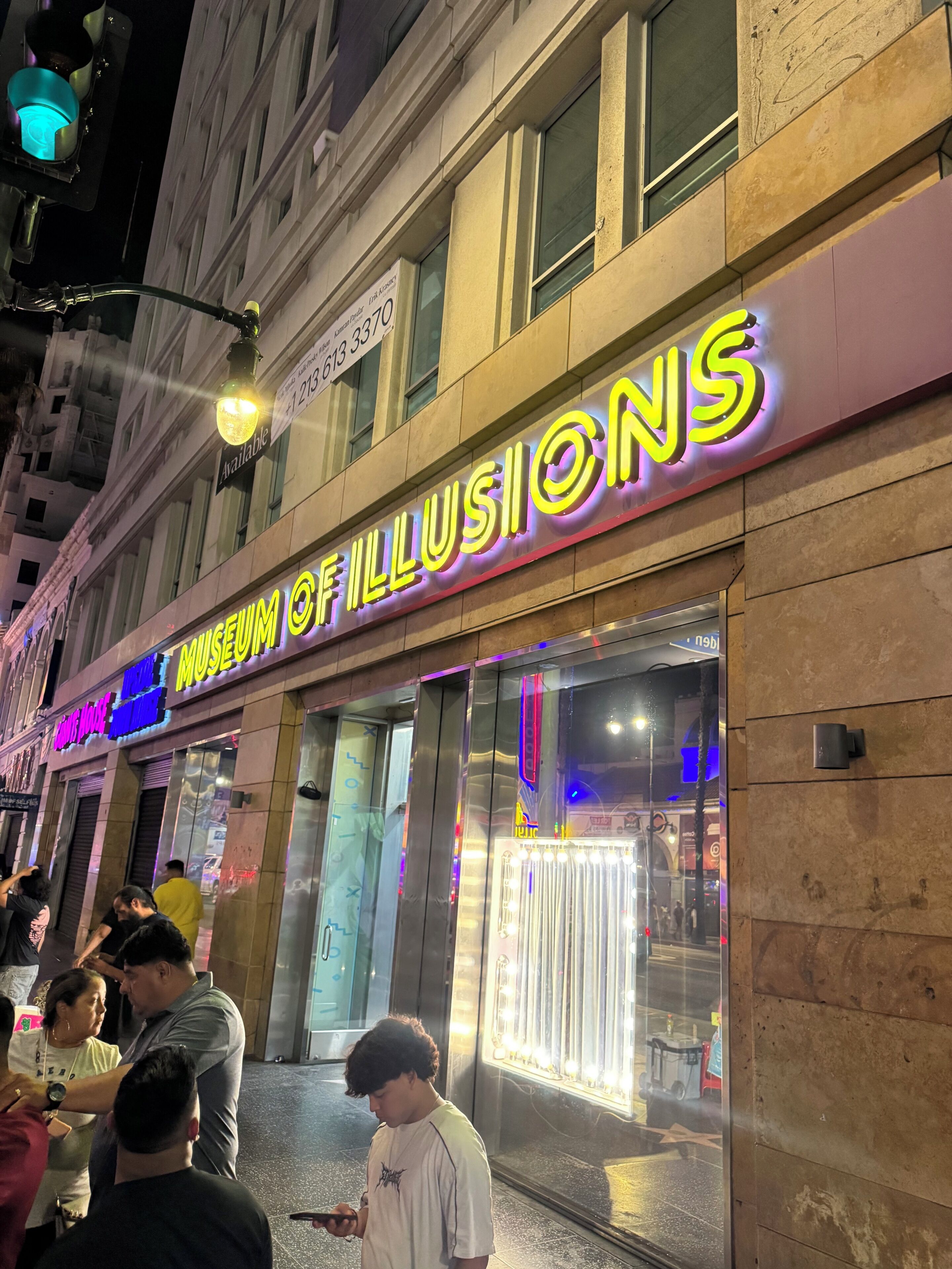 Een gebouw met een neonbord waarop 'Museum of Illusions' staat en een zichtbare etalage.