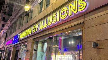 Een gebouw met een neonbord waarop 'Museum of Illusions' staat en een zichtbare etalage.