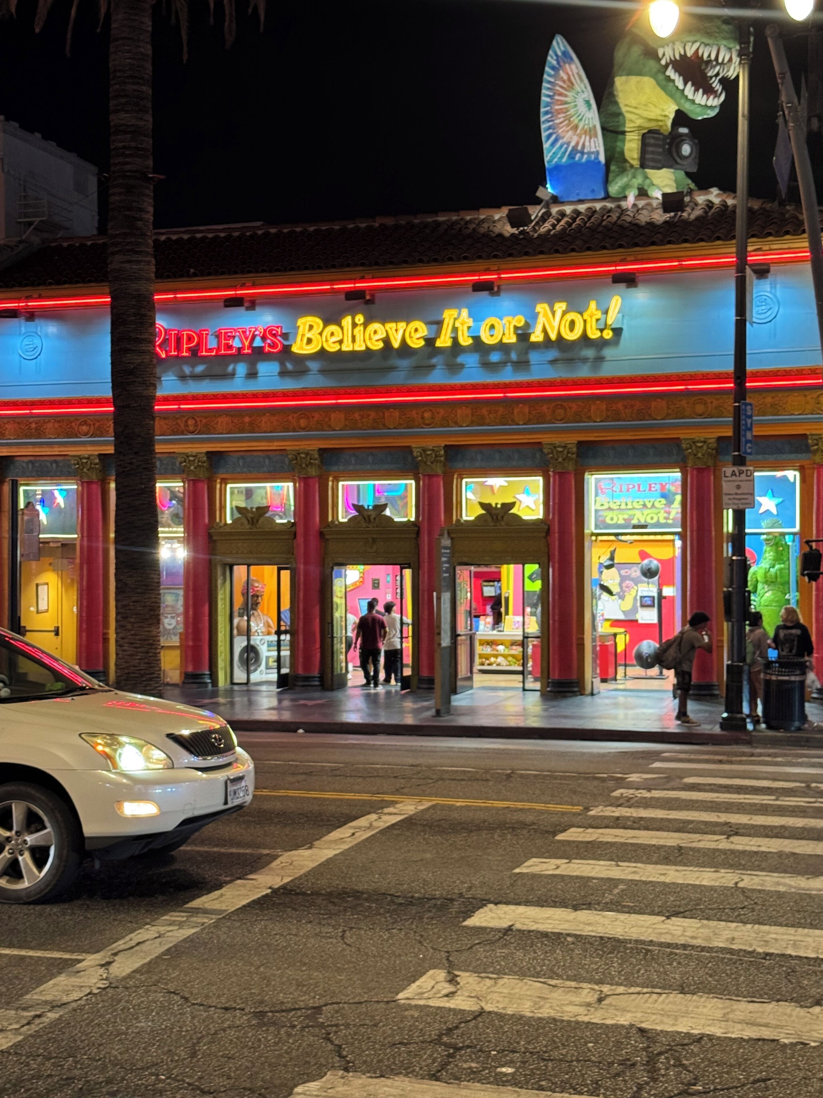 Ein hell erleuchtetes Schaufenster mit Neonreklame und einer großen Dinosaurierfigur.