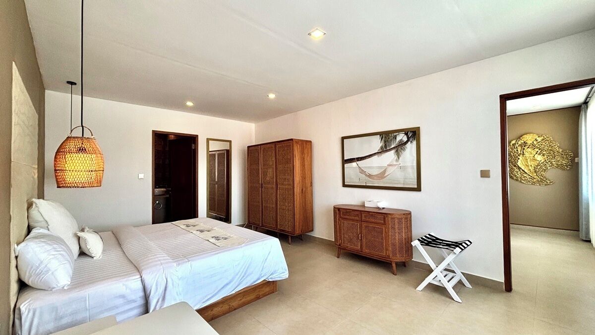 A bedroom with a bed, a wardrobe, a hanging light fixture, and a framed picture on the wall.