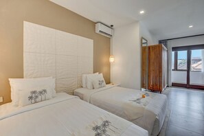 Habitación de hotel con dos camas, un ventanal grande y vista a la ciudad.