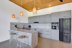 Una cocina moderna con armarios blancos, una isla de mármol y electrodomésticos de acero inoxidable.