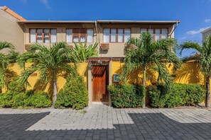 A two-story building with a tiled roof, a wooden door, and a paved entrance. - Villa Exquise (Legian)