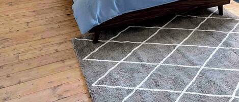 A bedroom with a bed, a bedside table, a lamp, and a rug.