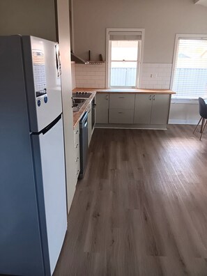 A kitchen with a refrigerator, stove, and cabinets.